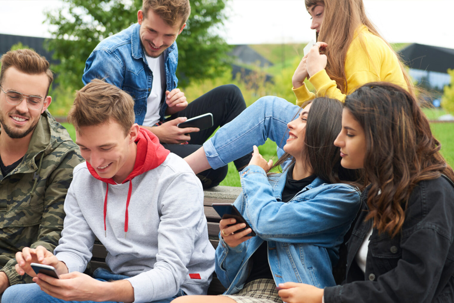 Jugendliche | Generation Z Jugendliche Gruppe sitzt zusammen und schaut auf Smartphones