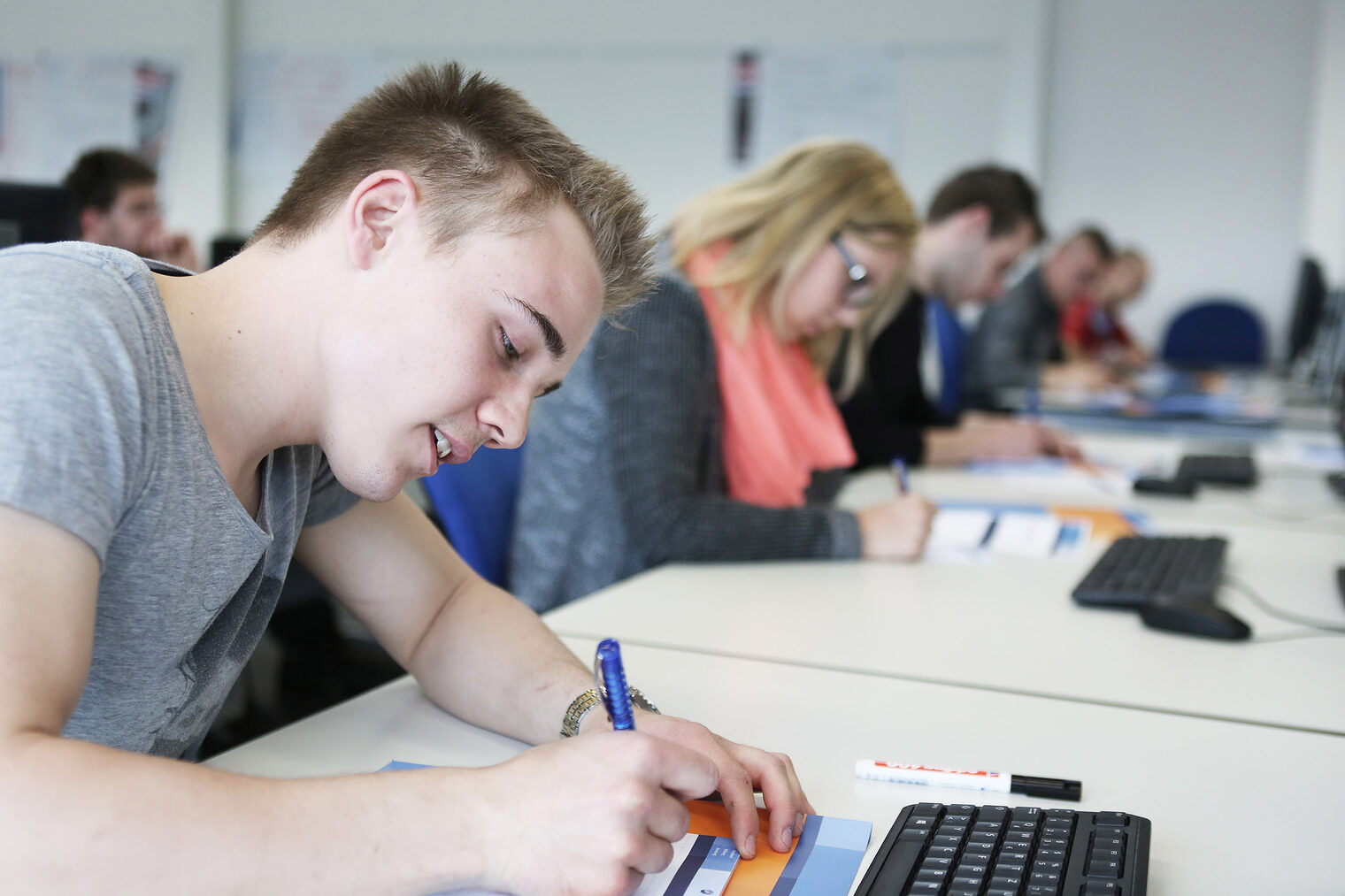 Nahaufnahme von Schüler an einem Tisch, der mitschreibt