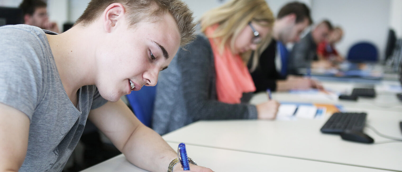 Kurse | Seminare Nahaufnahme von Schüler an einem Tisch, der mitschreibt