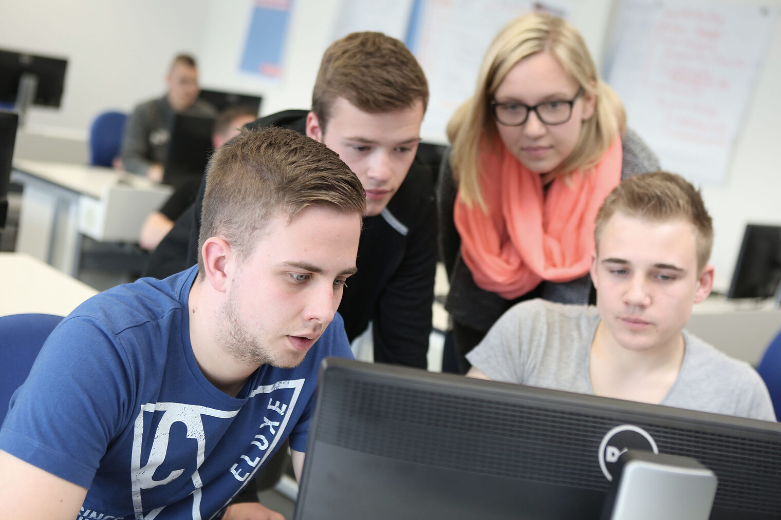 Unterrichtsraum, mehrere Schüler schauen auf einen Bildschirm