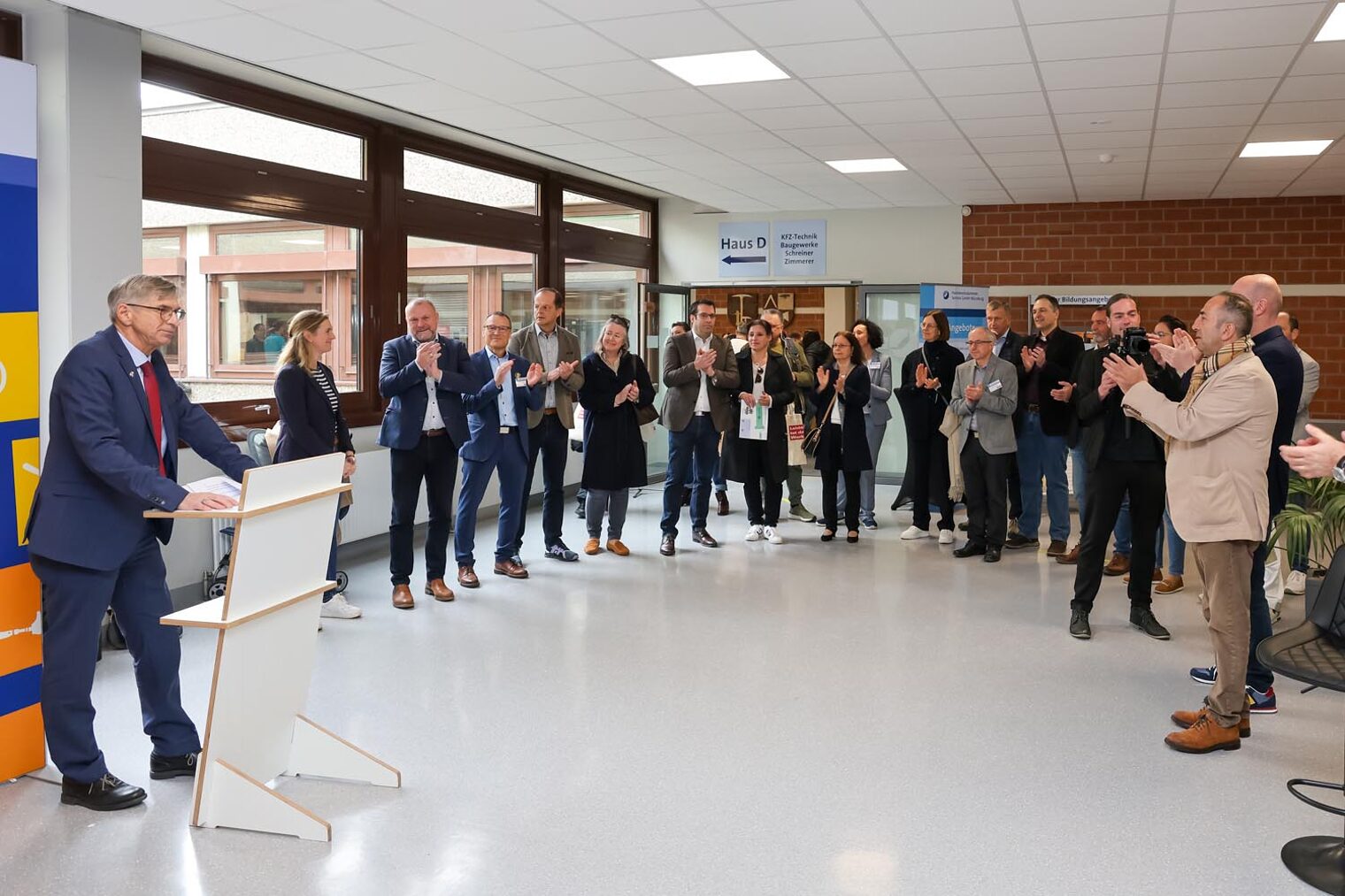 Handwerkskammer-Präsident Michael Bissert am Rednerpult und Ehrengäste stehen im Halbkreis