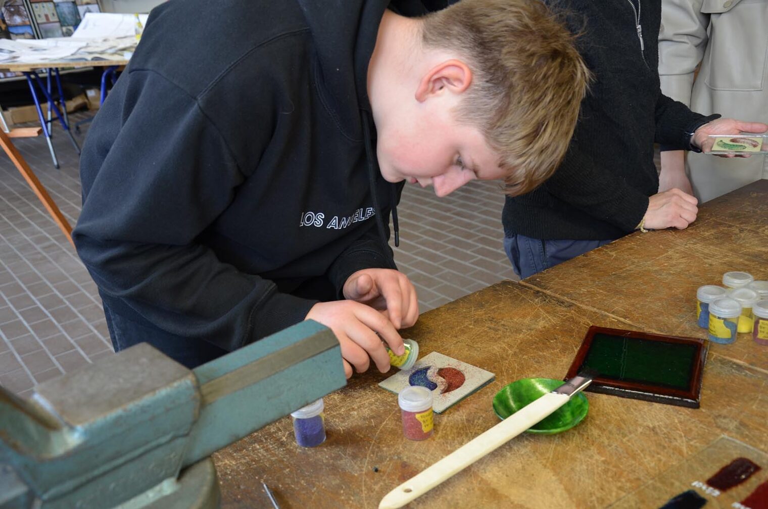 Besucher des Macher-Tags gestaltet ein Glas-Element in der Form von Yin und Yang