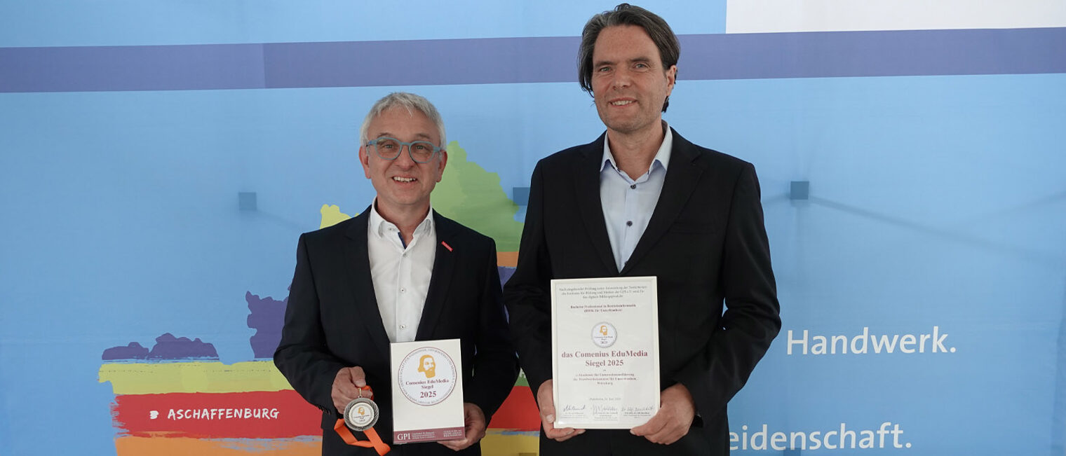 Comenius EdUMedia Siegel 2025 | Akademie für Unternehmensführung Foto zweier Personen, die Kamera blicken und Auszeichnung in den Händen halten