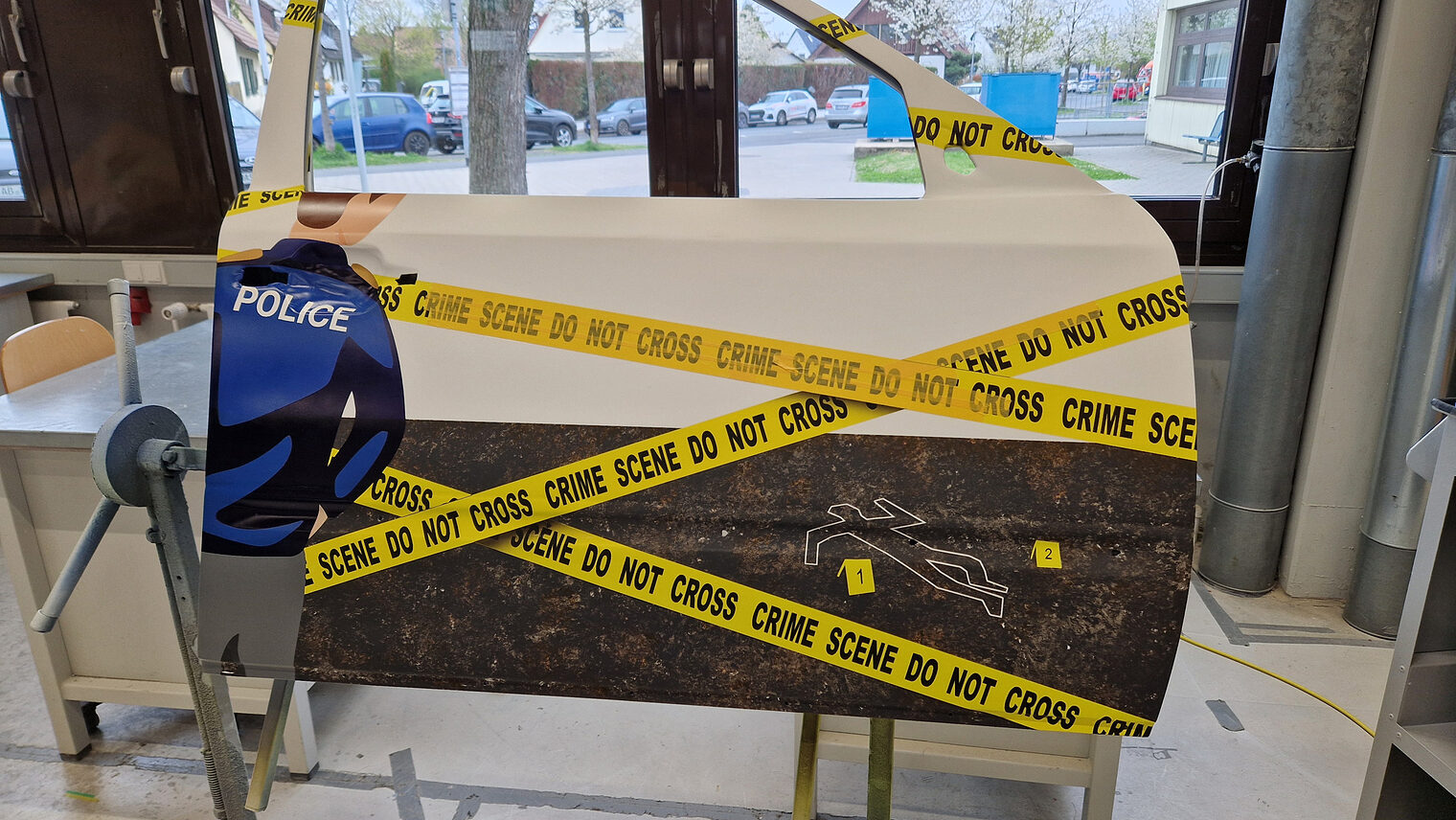 DMH 2025 | Kammersieger Gesellstück lackierte Autotür, zeigt einen Polizisten und gelbes Absperrband