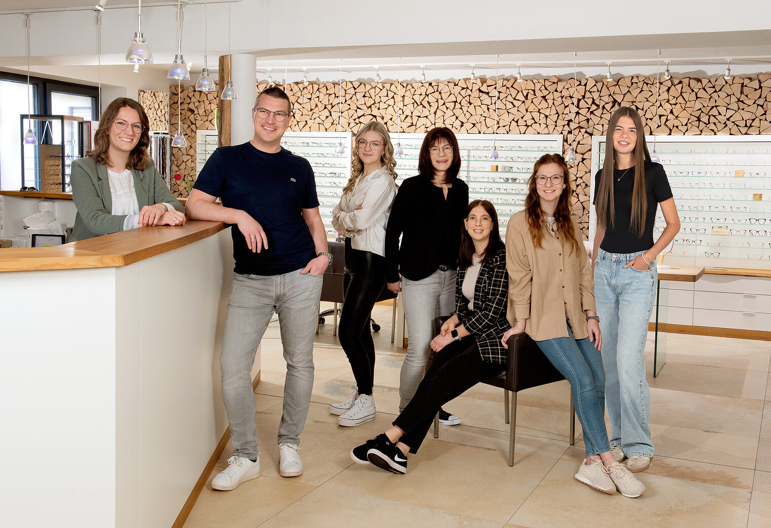 Team von Augenoptkern Auf dem Bild sieht man sieben Personen. Im Hintergrund sieht man viele Brillen