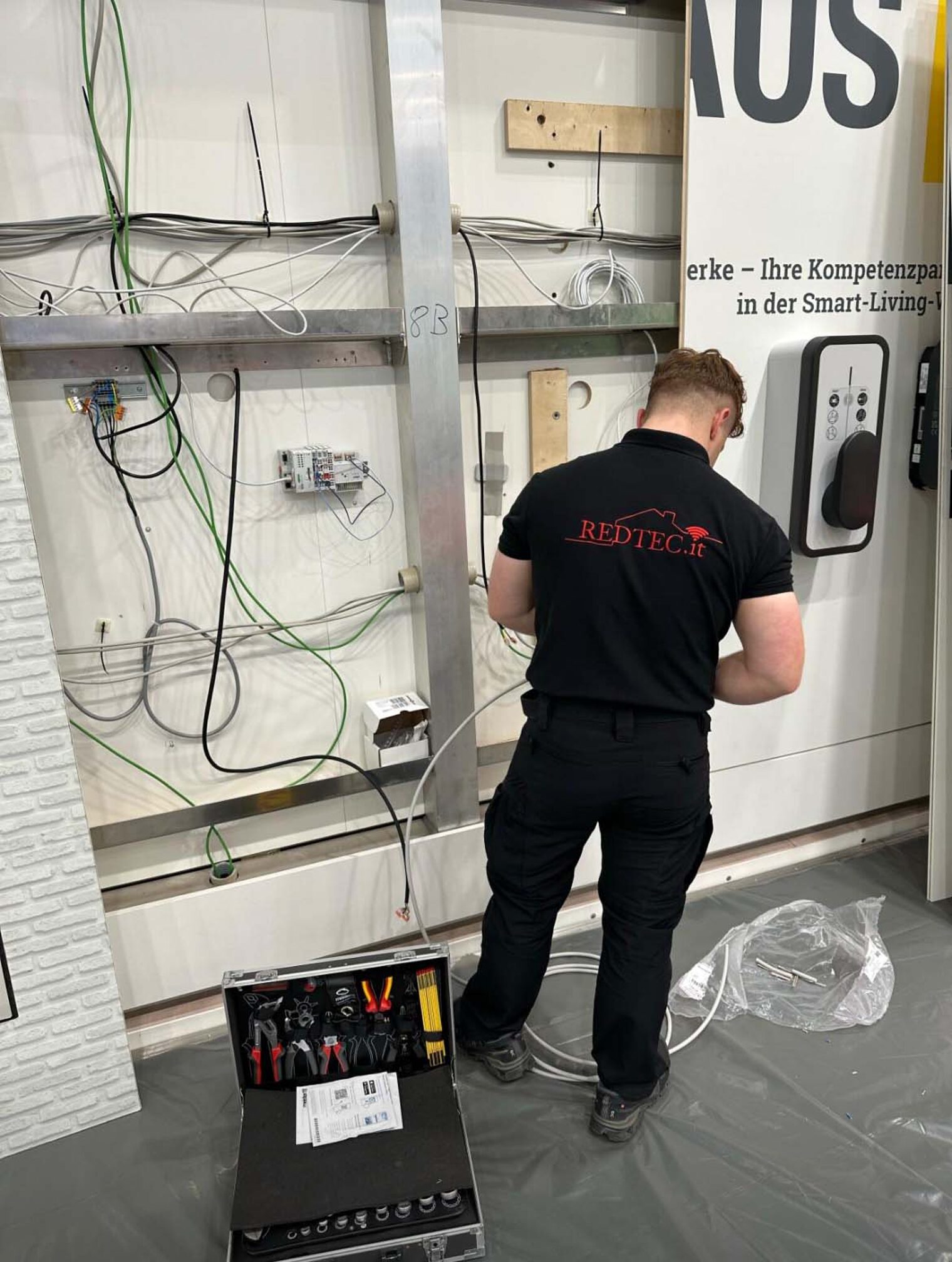 Elektroniker Gebäudesystemintegration  Elektroniker Gebäudesystemintegration steht vor einer Wand