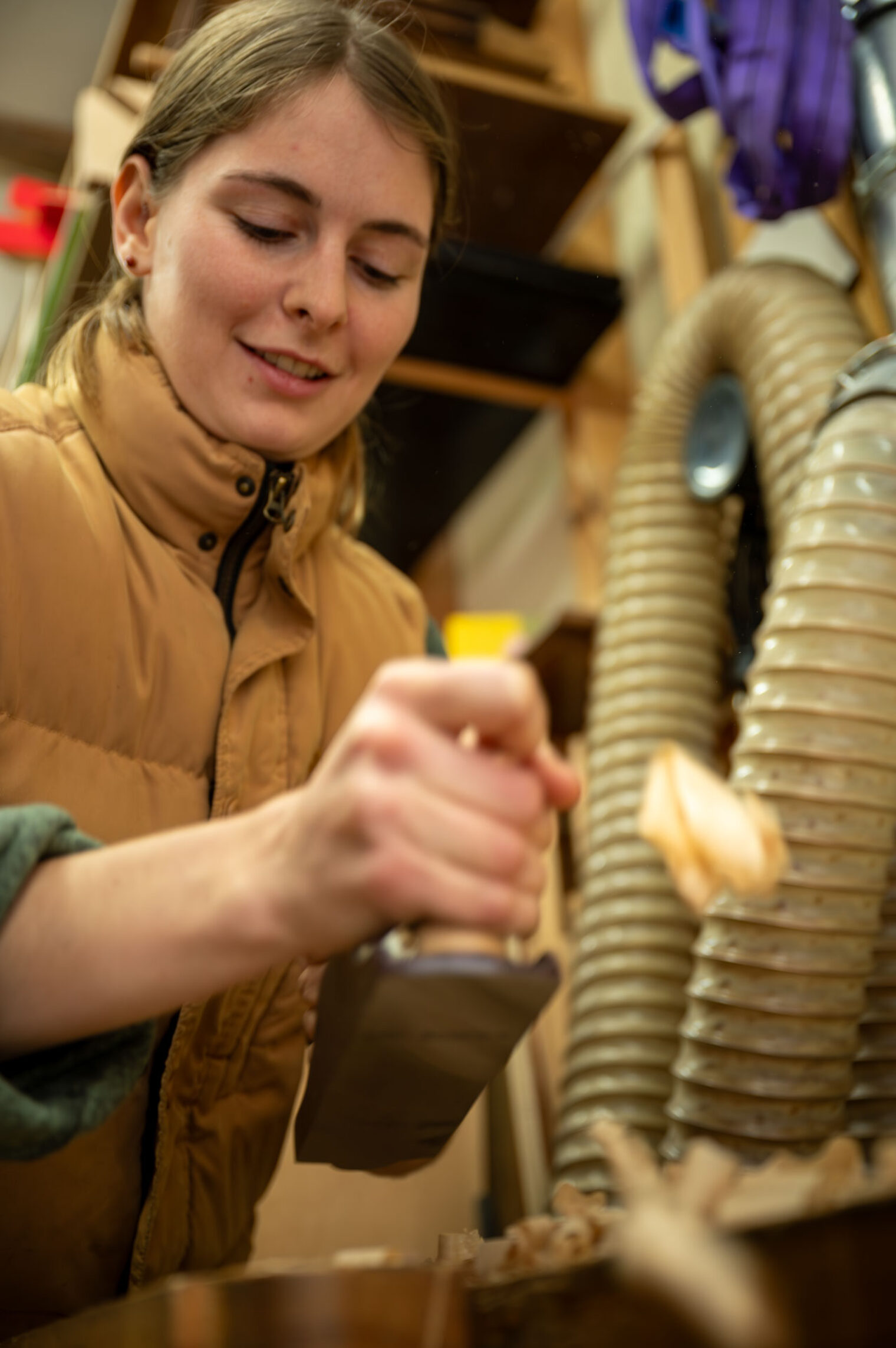 Junge Frau in Werkstatt hobelt Holz Junge Frau in Werkstatt hobelt Holz