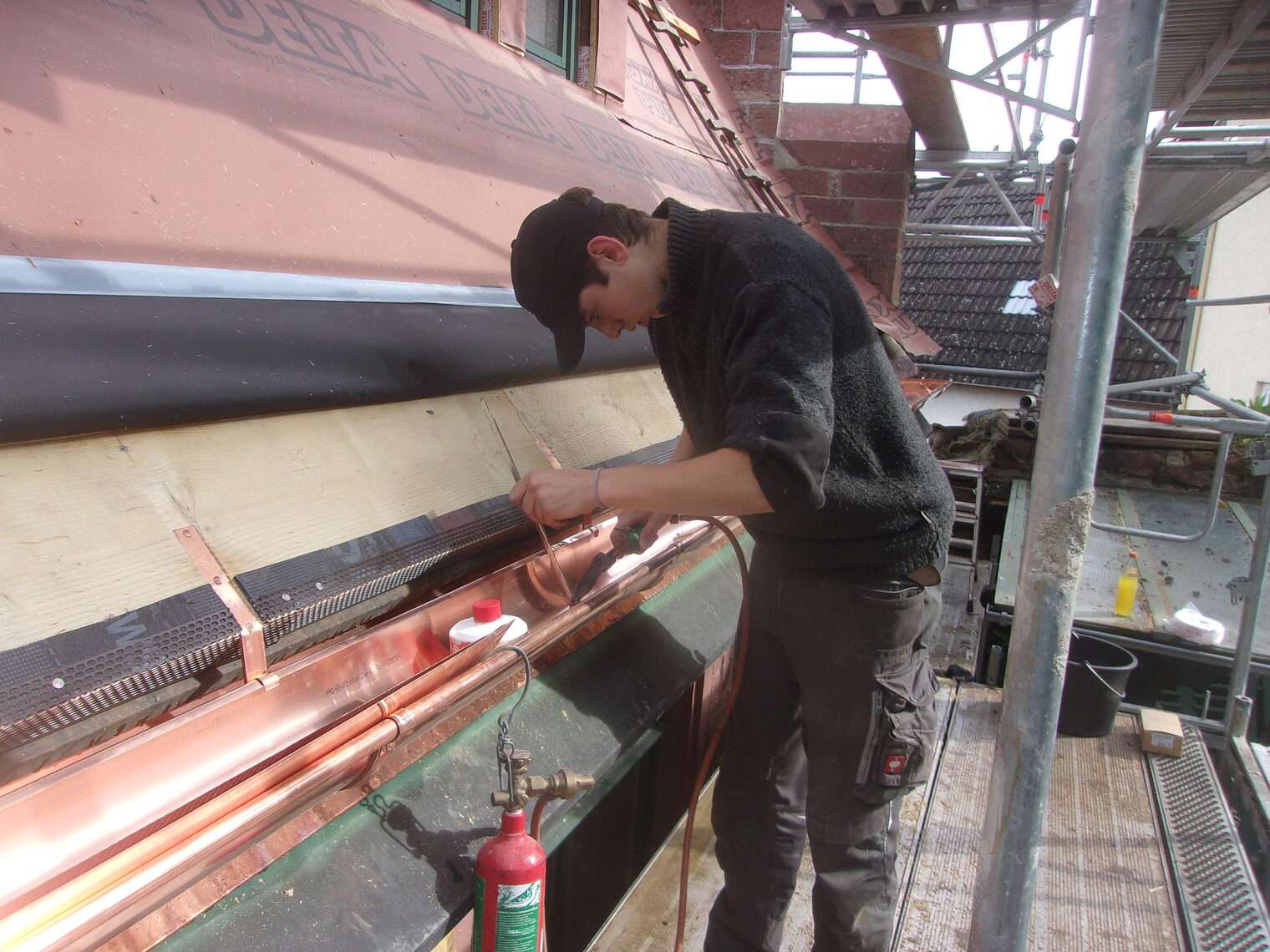 Junger Mann arbeitet an einer Dachrinne Junger Mann arbeitet an einer Dachrinne
