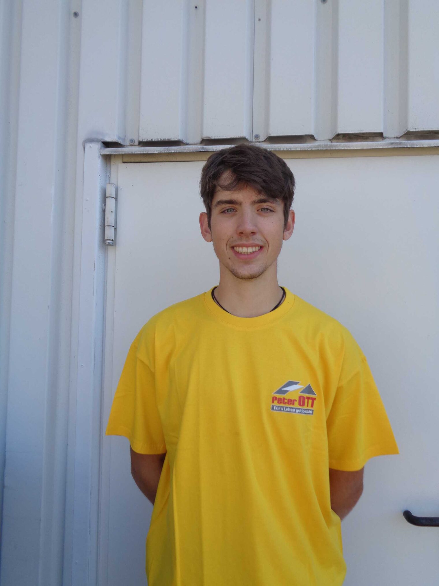 Junge in knallgelbem T-Shirt lächelt in die Kamera Junge in knallgelbem T-Shirt lächelt in die Kamera