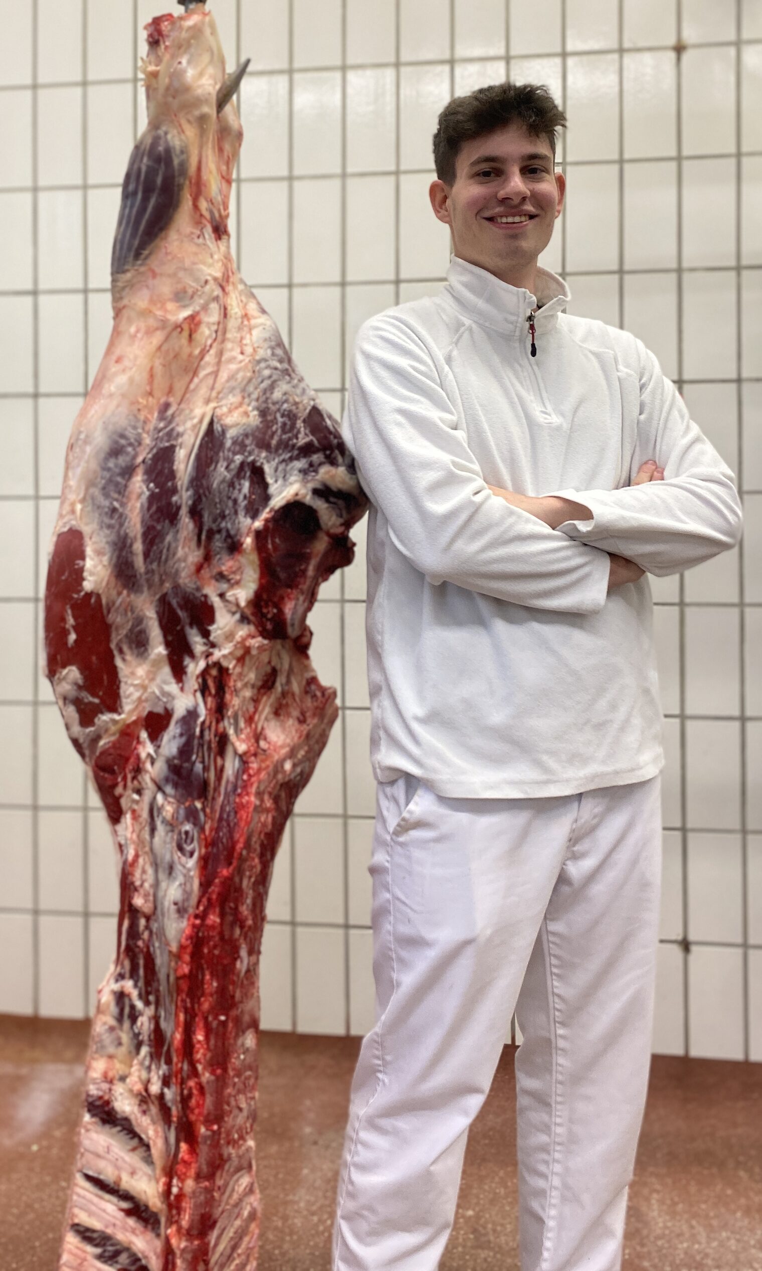 DMH 2025 | Kammersieger Junger Mann steht mit verschränkten Armen lächelnd neben einem zerlegten Tier