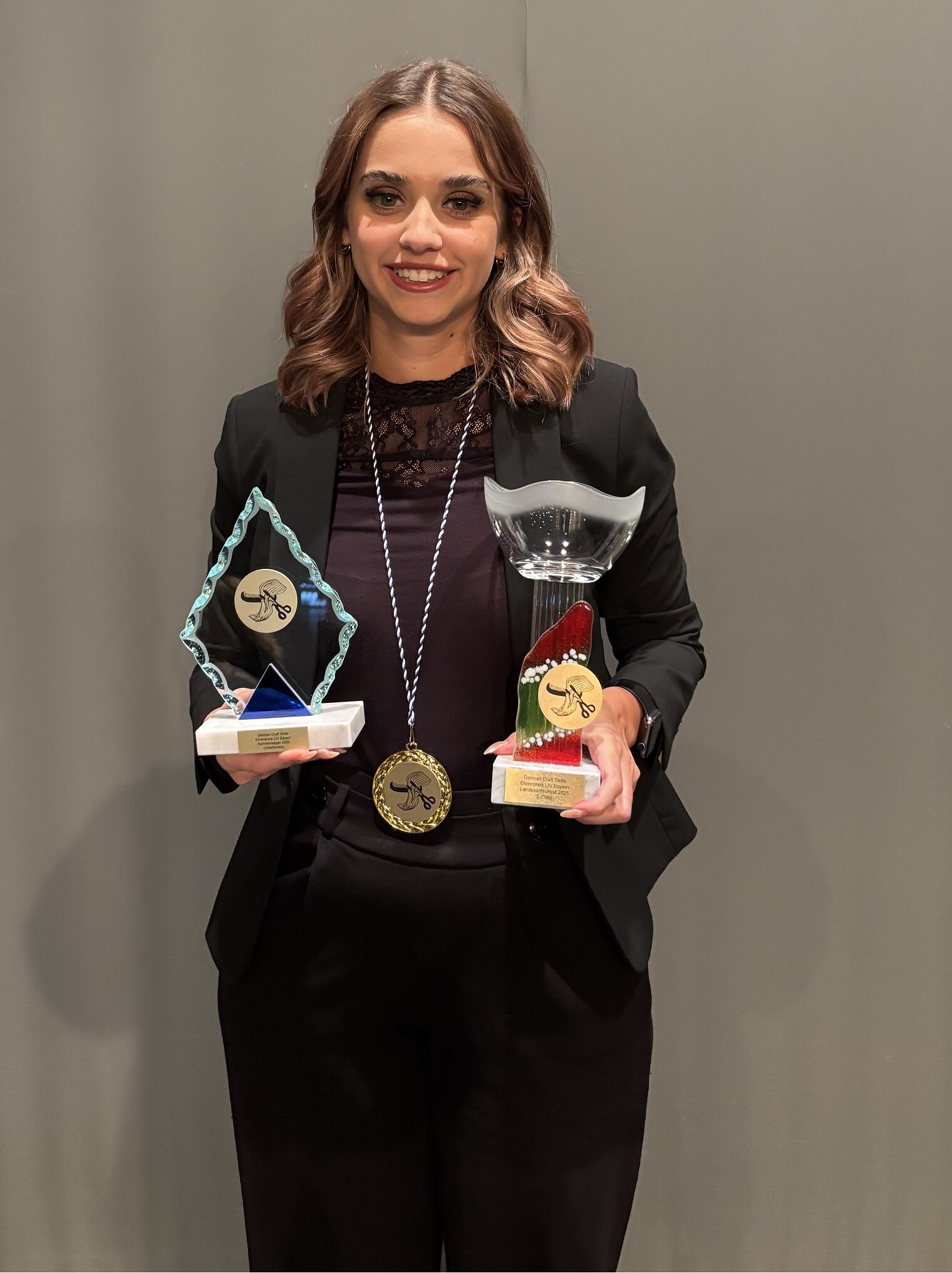 DMH 2025 | Kammersieger Junge Frau stehend mit zwei Pokalen in den Händen und einer Medallie um den Hals