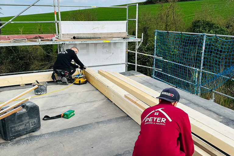 DMH 2025 | Kammersieger Baustelle, oben auf dem Dach, zwei Zimmerer arbeiten an Holzbalken