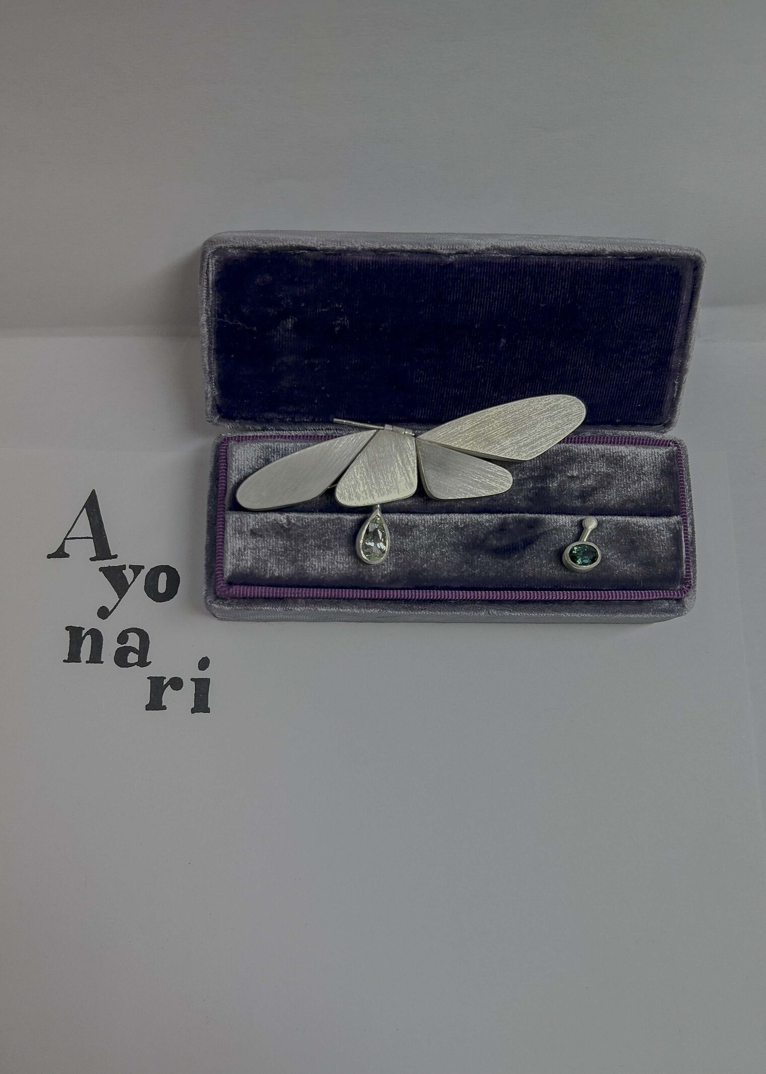 Schmuckstück mit Ähnlichkeit zu Schmetterling, grüner Stein eingefasst Schmuckstück in Schatulle mit Ähnlichkeit zu Schmetterling, grüner Stein eingefasst, Text "A yo na ri"