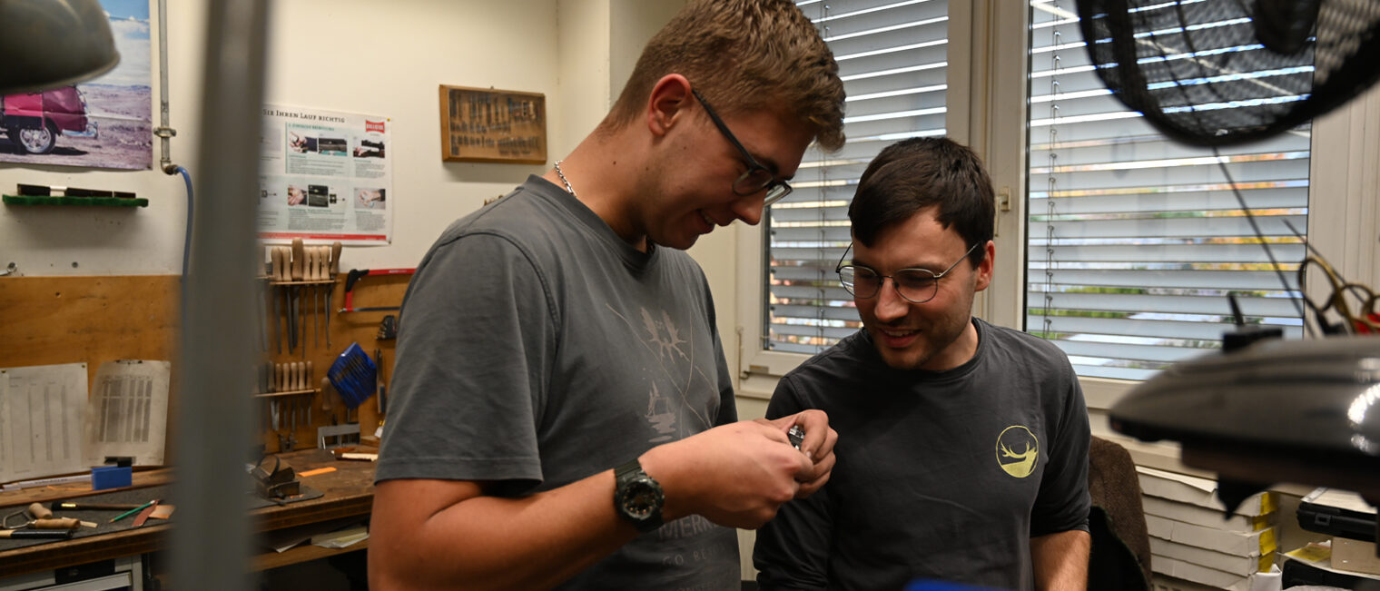 Zwei Männer in einer Werkstatt, schauen gemeinsam auf ein Werkstück