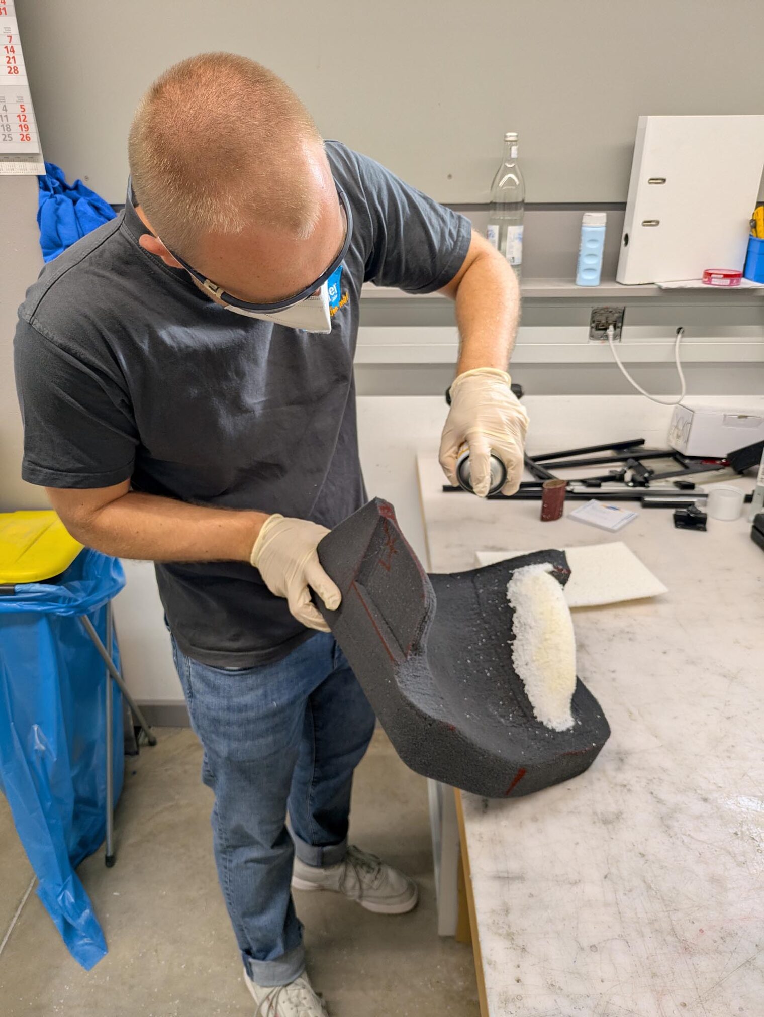 Orthopädiemechaniker an Werkbank sprüht Schaum auf etwas