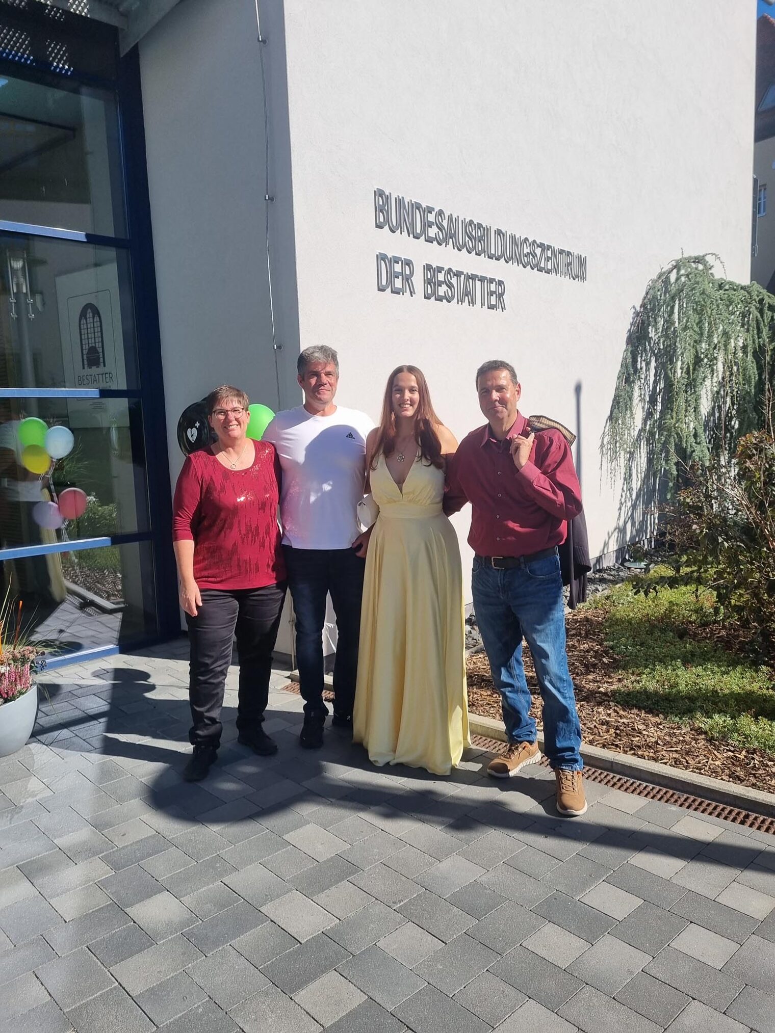 Gruppenfoto vier Personen vor Ausbildungszentrum bei Abschlussfeier